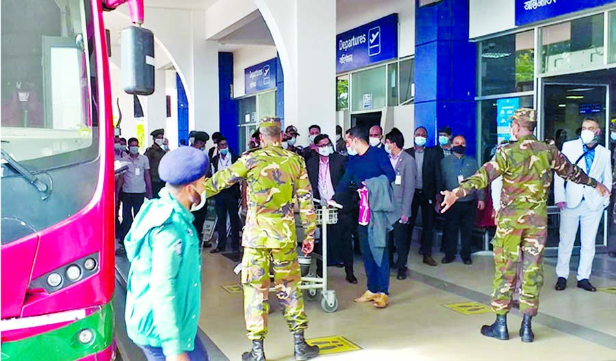Army personnel guide UK returnees to BRTC buses upon their arrival at Osmani International Airport in Sylhet on Monday. Expatriates were taken to Hotel Holy Gate in Sylhet city to maintain a mandatory 14-day institutional quarantine.