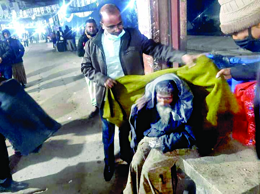 Deputy Commissioner (DC) of Kishoreganj Mohammad Shamim Alam distributing warm cloths among the cold - hit people at local Rail Station platform on Monday night.