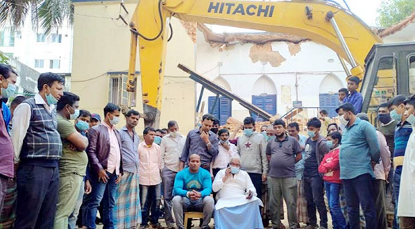 Prosecutor International War Crimes Tribunal Advocate Rana Dasgupta alongwith locals seen sitting beside the bulldozer meant for demolition of historic residence of Jatra Mohan Sen in the port city.