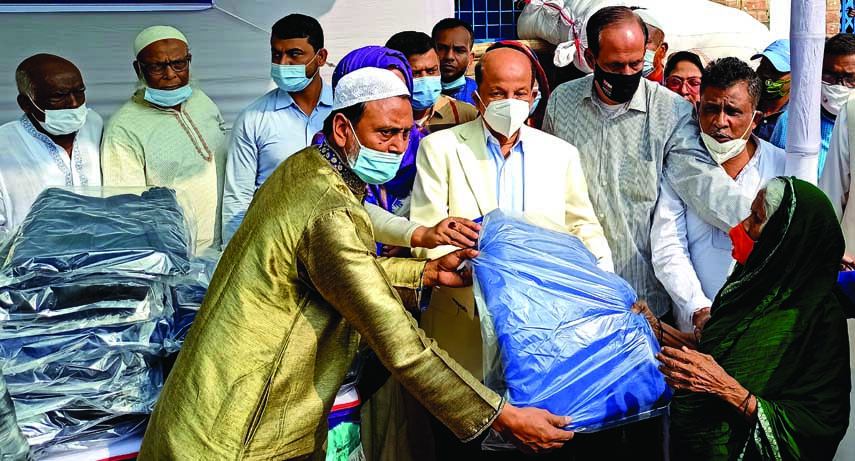 State Minister for Industries Kamal Ahmed Majumder distributes winter clothes among the cold-hit poor people on the premises of the city's Hazi Ali Hossain High School on Saturday.