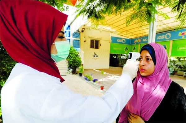 A healthcare worker checks the temperature of a woman in Gaza City.