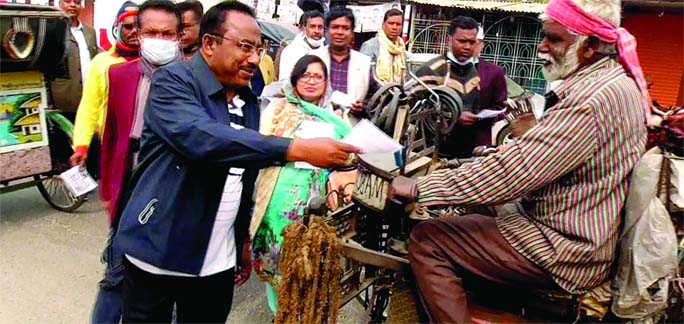 Isahaq Ali Malitha, Awami League-nominated mayoral candidate for upcoming Ishwardi municipal elections distributes leaflet to a man during an election campaign on Tuesday.
