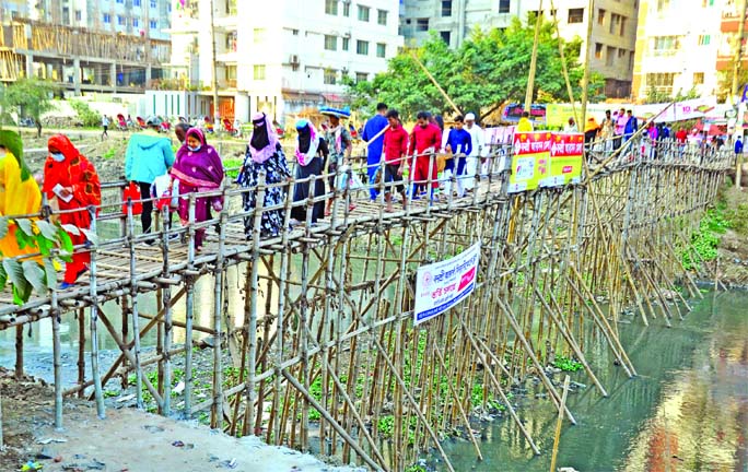 A bamboo bridge has been set up on the Rampura canal to connect the capital's Bonosree and Aftabnagar areas. Locals use the makeshift structure amid risk as their cry for building a concrete bridge has failed to bring any result. This photo was taken on