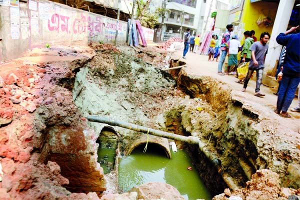 Pedestrians walk beside a huge hole as construction firms excavate roads aimlessly as a result, the sufferings of the city dwellers mounted. This photo was taken from Boro Moghbazar area in the capital on Friday.