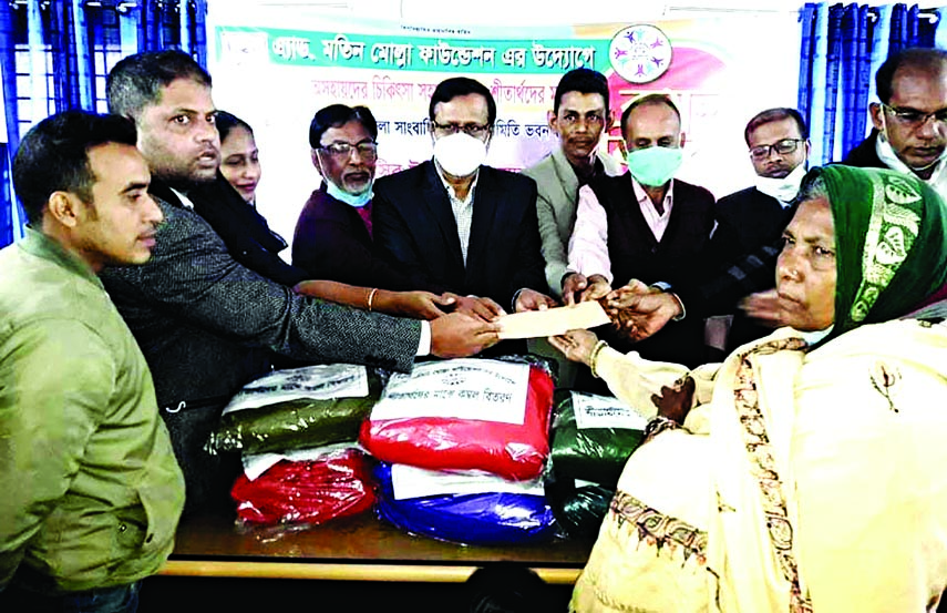 Madaripur District Primary Education Officer Nasir Uddin Ahmed distributes winter clothes and medical aid equipment among the cold-hit poor people organised by Advocate Matin Molla Foundation at Madaripur Zilla Sangbadik Kalyan Samity Bhaban on Monday.