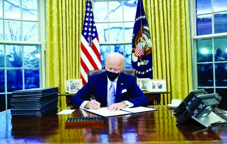 US President Joe Biden signs a series of executive orders at the Resolute Desk in the Oval Office just hours after his inauguration on January 20.