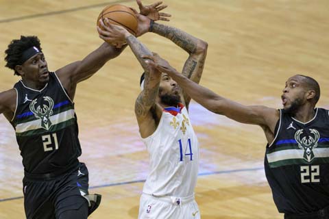 New Orleans Pelicans forward Brandon Ingram (14) shoots from between Milwaukee Bucks guard Jrue Holiday (21) and forward Khris Middleton (22) during the first half of an NBA basketball game in New Orleans on Friday.