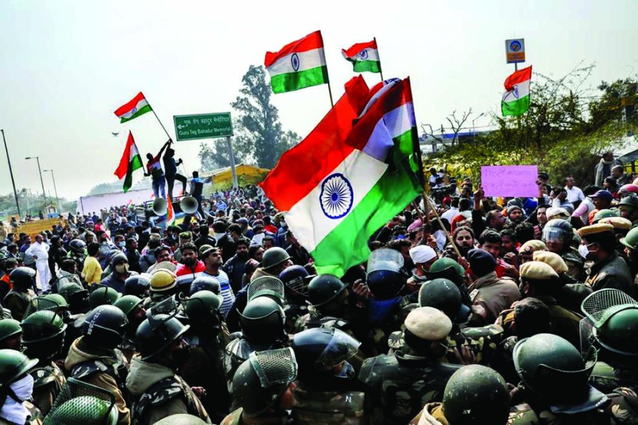 People shout anti-farmers slogans and wave India's flags as police officers try to stop them, at a site of the protest against farm laws at Singhu border near New Delhi, India.