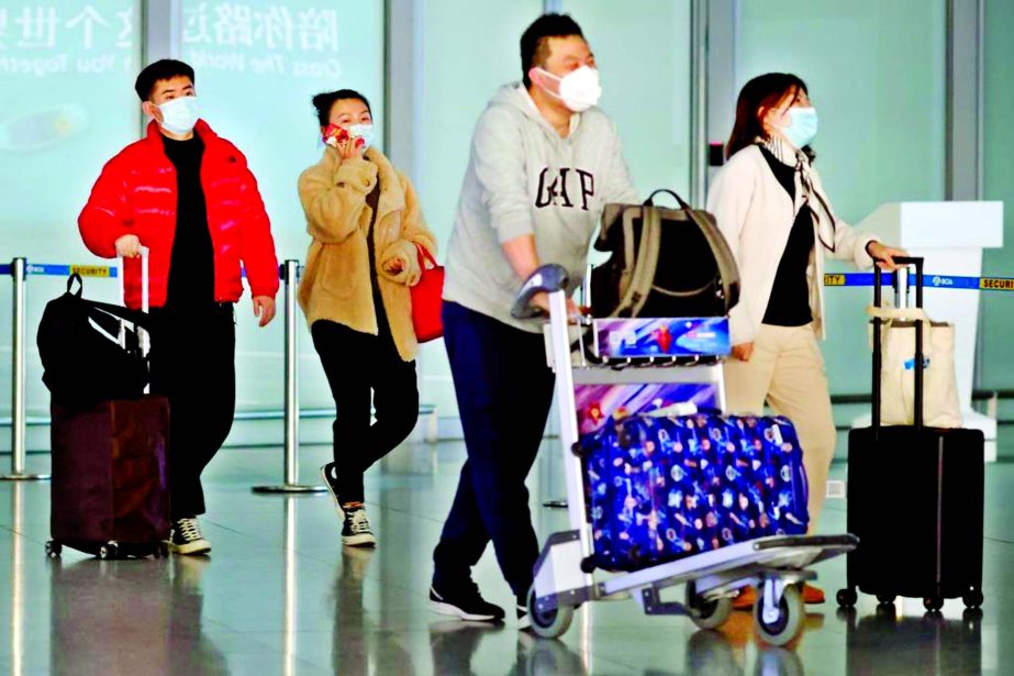 People wearing protective face masks carry their luggage at Capital Airport, following an outbreak of the Covid-19, in Beijing, China.