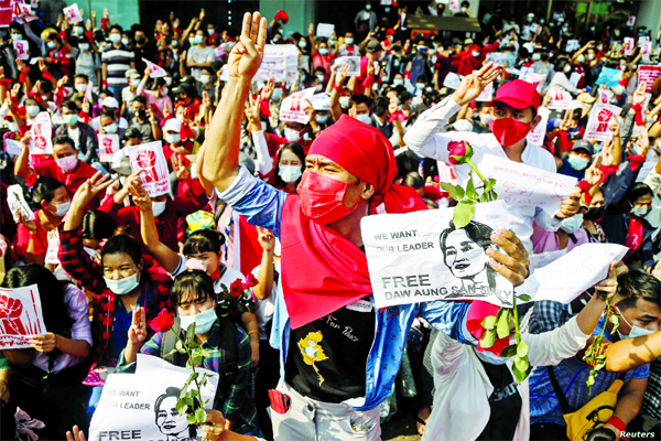 People show the three-finger salute and hold signs demanding the release of elected leader Aung San Suu Kyi as they take part in a protest against the military coup, in Yangon, Myanmar.