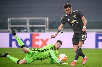 Manchester United's Portuguese midfielder Bruno Fernandes (right) scores a goal past Real Sociedad's Spanish goalkeeper Alex Remiro during the UEFA Europa League round of 32 first leg soccer match between Real Sociedad and Manchester United at the Allia