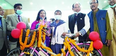 Railways Minister Advocate Md. Nurul Islam Sujan MP distributing bi-cycles among disadvantaged people of indigenous community at Boda Upazila Parishad Auditoirium in Panchagarh on Friday.