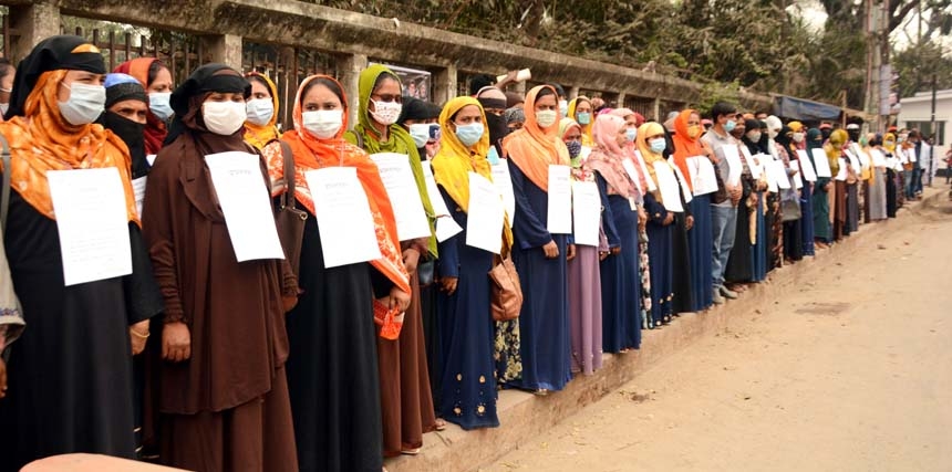 Employees of Supreme Knitwear form a human chain in front of the Jatiya Press Club on Saturday demanding withdrawal of lay-off of the factory.