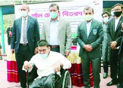 Md Sheikh Yousuf Harun, Secretary of the Ministry of Public Administration, distributes wheel-chairs at a programme held on the Naogaon DC office premises on Saturday.