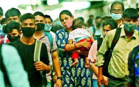 A woman carrying a child walks inside a railway station amidst the spread of the coronavirus, in Mumbai, India.