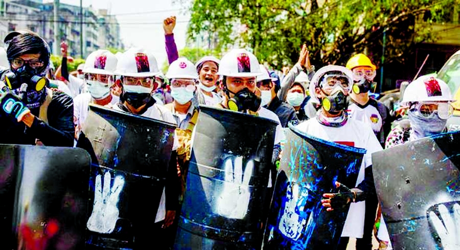 Demonstrators hold shields as they face riot police during a protest against the military coup in Yangon, Myanmar.