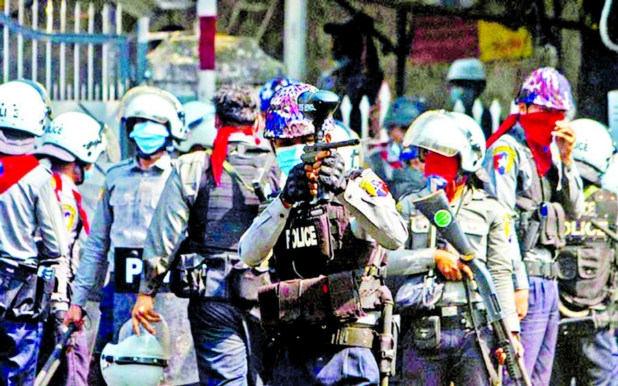 A riot police officer fires a rubber bullet toward protesters during a protest against the military coup in Yangon, Myanmar