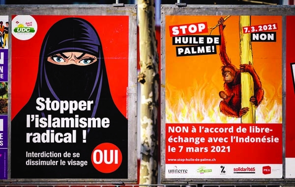 A photograph taken on March 1, 2021 in Geneva shows two campaign posters, one in favour of a "burqa ban"(L) and the other (R) against a free trade agreement with Indonesia ahead of a nationwide vote by Swiss citizen on Sunday.