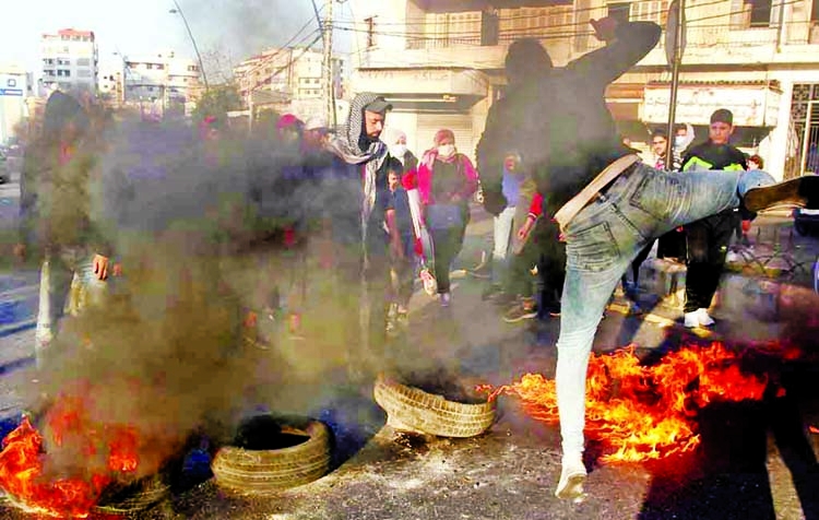 Demonstrators block a road with burning tyres during a protest against the fall in Lebanese pound currency and mounting economic hardships, in Sidon, Lebanon.