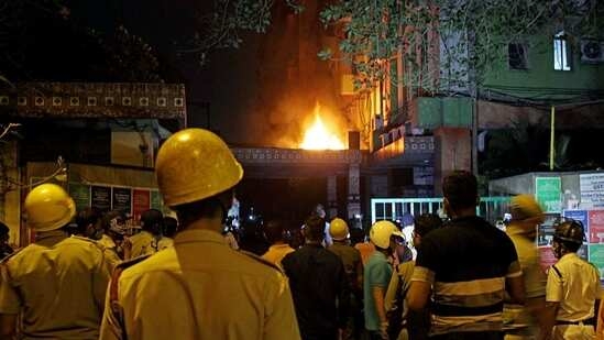 Firefighters and locals stand and watching fire after it broke out on the 13th floor of a multi-storeyed building and housing offices of the Railways, on Strand Road in Kolkata on Monday.
