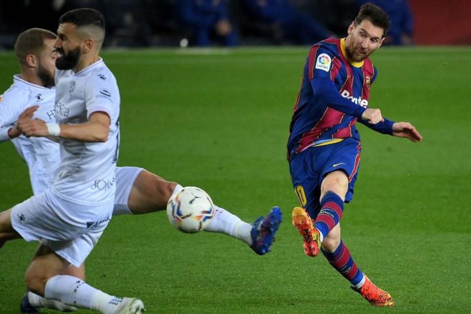 Barcelona's forward Lionel Messi (right) scores his team's fourth goal during the Spanish League football match between Barcelona and SD Huesca at the Camp Nou stadium in Barcelona on Monday