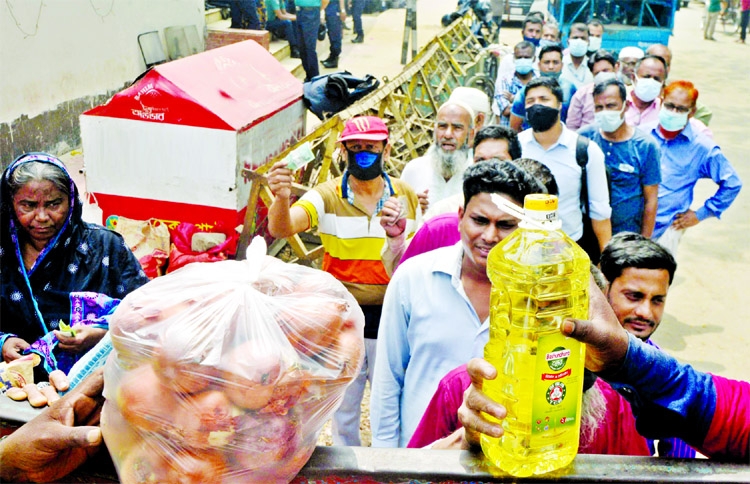 Buyers stand in a long queue to purchase edible oil and onions from TCB truck open market sale in front of the Secretariat on Tuesday.