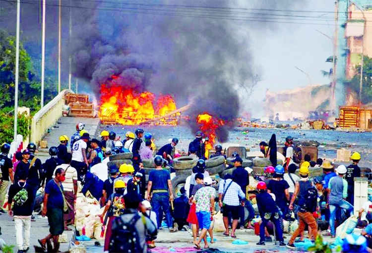 Anti-coup protesters stand at a barricade as they clash with security forces on Bayint Naung Bridge in Mayangone, Yangon, Myanmar.