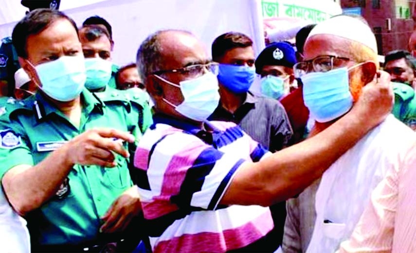 Rangpur City Corporation Mayor Mostafizur Rahman Mostafa distributes masks among the people on behalf of the Rangpur Metropolitan Police on City Bazar premises in the corporation on Sunday.