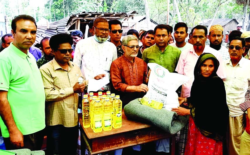 Abdul Hamid, Upazilla Chairman of Chatmohor of Pabna District and Secretary of Upazilla Red Crescent Society distributes relief materials among thirteen fire victim families of Hogolbaria village under Dibgram union on Friday.