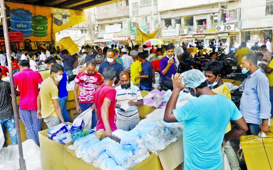 People throng a wholesale market to purschase masks as government puts more emphasis on mantaining health rules due to spike of Coronavirus infections recently. This photo was taken under Babu Bazar Bridge at Mitford area in the capital on Tuesday.