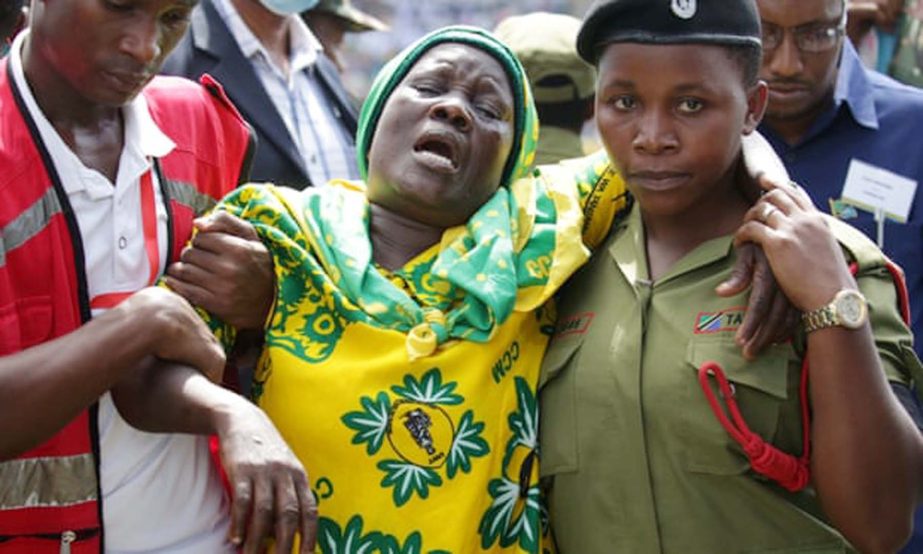 Volunteers assist a civilian at the funeral procession of President John Pombe Magufuli.