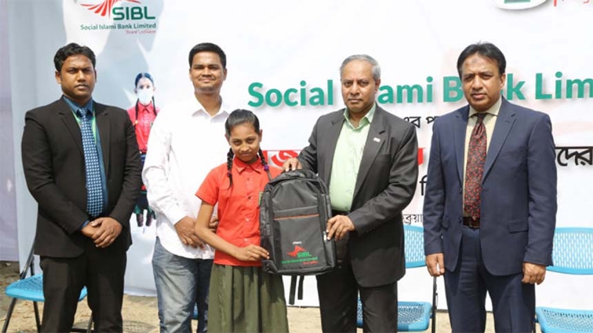 Md Sirajul Hoque, DMD of Social Islami Bank Limited (SIBL), handing over the bags among the students of Mojar School, an Odommo Bangladesh Foundation initiative, in the capital on Sunday. Senior officials of the bank were present.