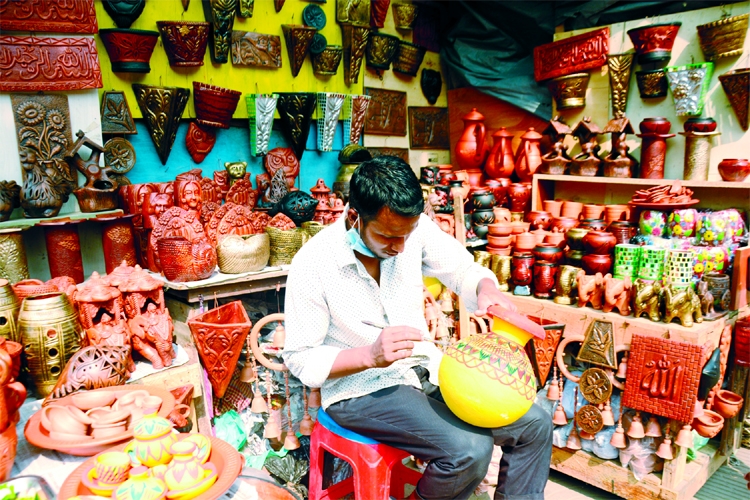 An artisan is seen painting a pitcher ahead of Pahela Boishakh in front of Shishu Academy in the capital on Sunday.