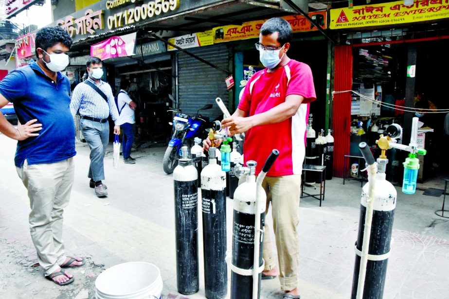 A man is seen examining portable oxygen cylinders as its demand and price went up due to coronavirus surge the across the country.