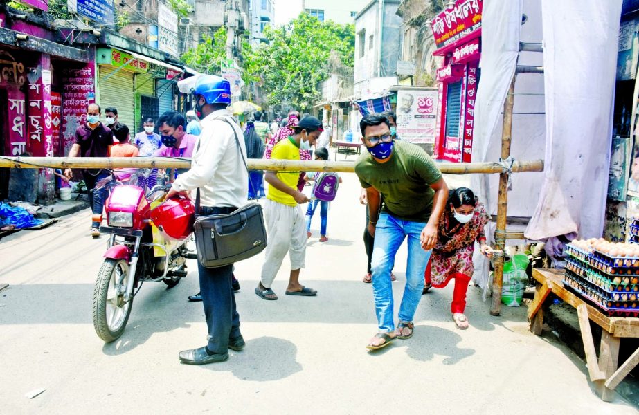 People crossing the road under the bamboo barricade during the lockdown. The snap was taken from Sarat Gupta Road in the city's Narinda on Thursday.