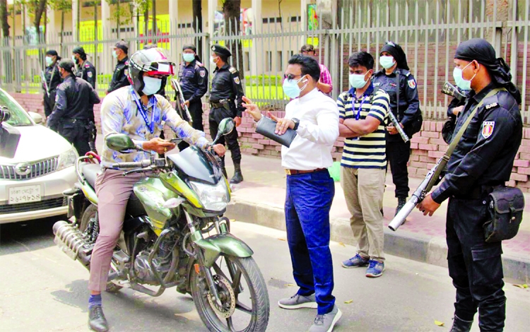 Executive Magistrate of the Mobile Court of RAB checking the movement pass of the motorists in the city's Shahbagh area on Friday.