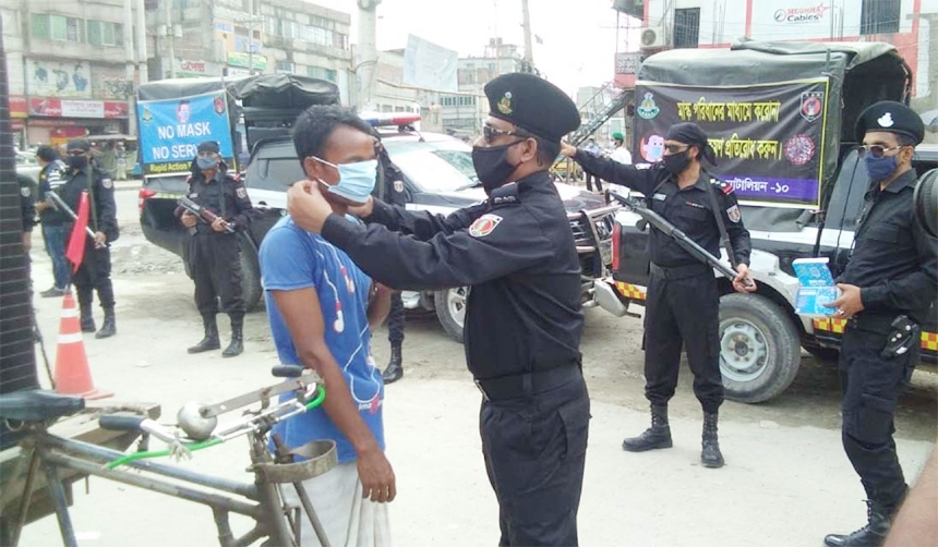 Law enforcers give masks among the commoners including rickshaw-puller as part of a drive to raise mass awareness about corona pandemic. The snap was taken from Keraniganj on Friday.