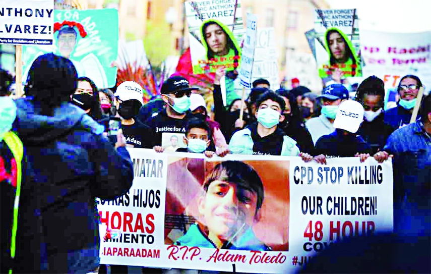 Protesters hold a banner as they demonstrate a day after officials released a graphic body-camera video showing a police officer shooting and killing 13-year-old Adam Toledo two weeks ago while he appeared to be raising his hands, in Chicago, Illinois, US