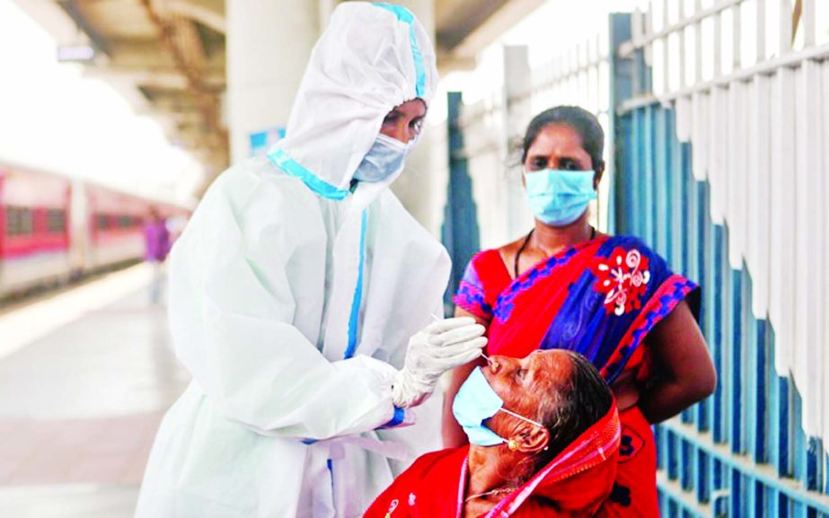 A healthcare worker in personal protective equipment (PPE) collects a swab sample from a woman, amidst the spread of the coronavirus, at a railway station in Mumbai, India.