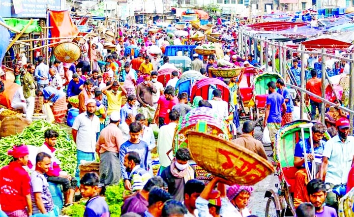 Porters and day-labourers all out to earn their livelihood as transactions are on at a kitchen market in Dhaka on Monday.