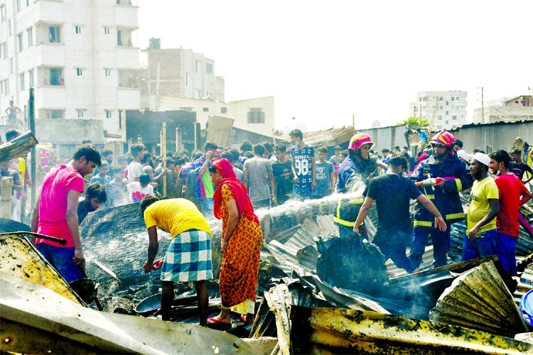 Fire fighters along with the local people douse fire that gutted more than 200 shanties at Balur Math slum under Turag Thana of Uttara in the capital on Wednesday.
