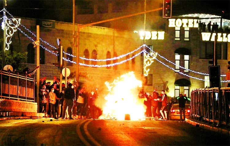 Palestinians stand around a burning barricade during clashes with Israeli police, as the Muslim holy fasting month of Ramadan continues, in Jerusalem.