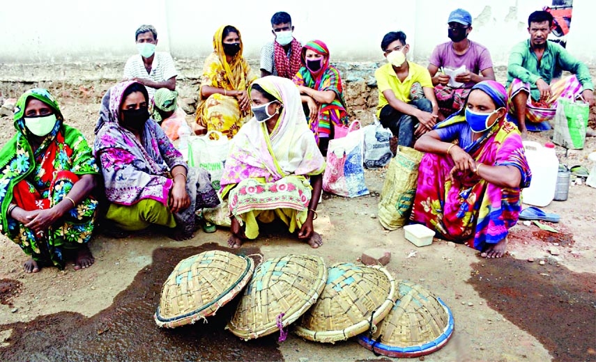 Day- labourers sit idle with their baskets at Azimpur area in the capital on Saturday as there was no work to maintain their livelihood amid strict lockdown.