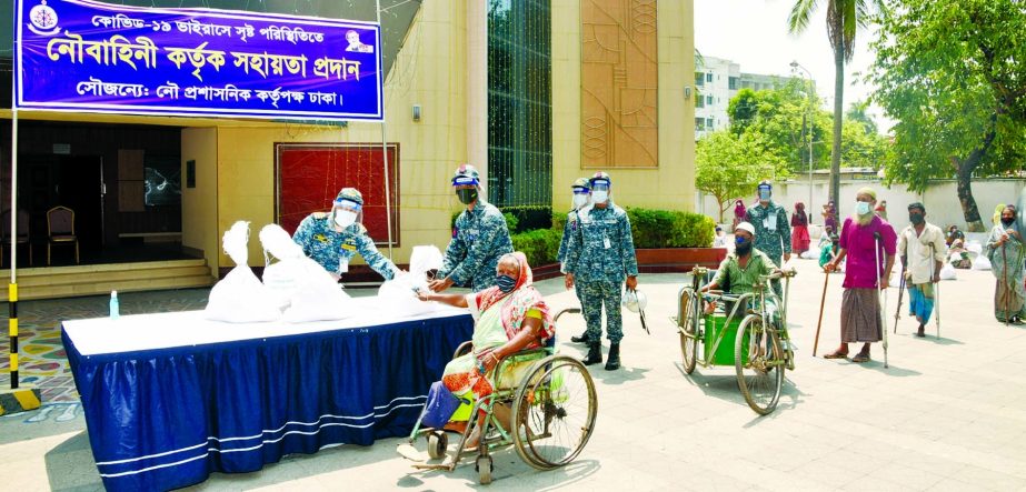 Bangladesh Navy personnel distribute food items and financial aid among the helpless and destitute people at Bhasan Tek area in the capital to tackle Corona on Sunday. ISPR photo