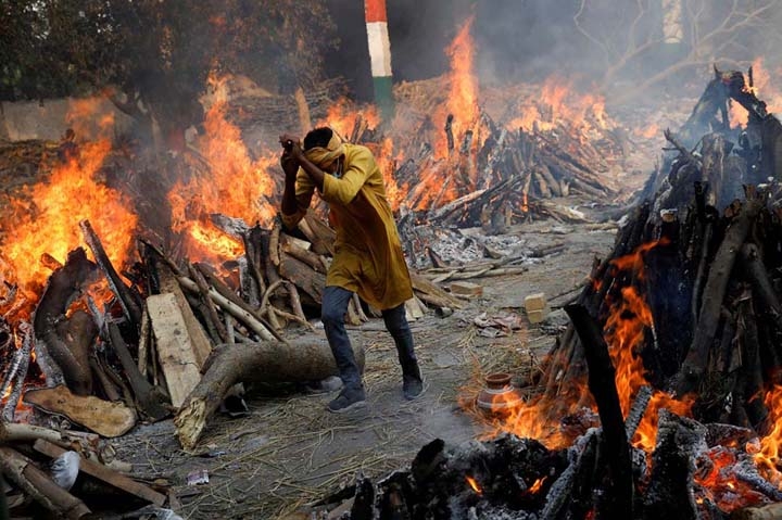 A man runs past the burning funeral pyres of those who died from the coronavirus disease (Covid-19), during a mass cremation, at a crematorium in New Delhi, India.