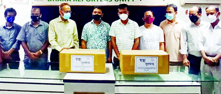 Health Affairs Secretary of BNP Central Committee Dr. Rafiqul Islam hands over personal protective equipment to DRU President Mursalin Nomani for its members at DRU auditorium on Thursday.