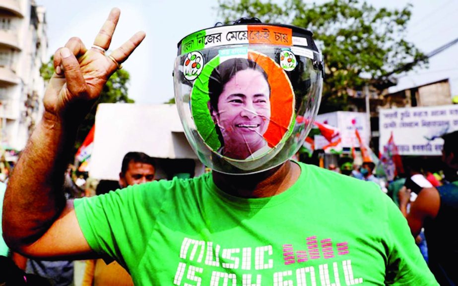 A supporter of the Chief Minister of West Bengal state and the Chief of Trinamool Congress (TMC) Mamata Banerjee, wearing a face shield with her image on it, gestures during celebrations after the initial poll results, amid the spread of coronavirus disea