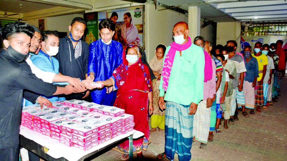 Kotwali Thana Chhatra League President Sumon Miah distributes iftar items among the distressed people at Sadarghat Terminal area in the city on Monday.