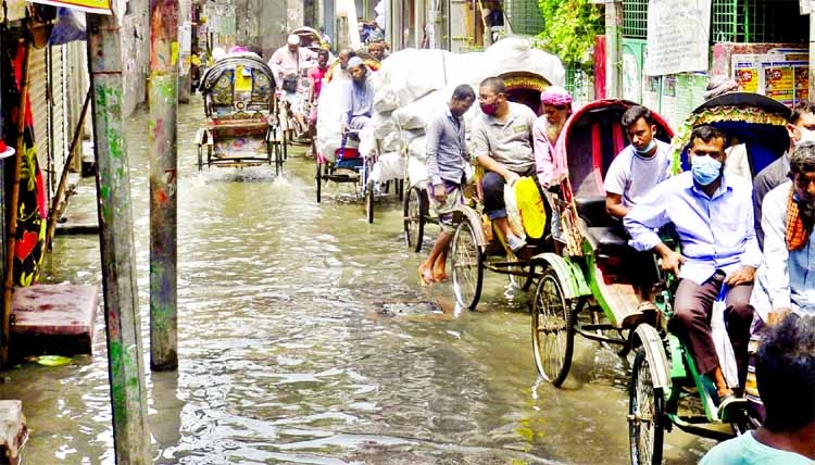 Rickshaw pullers carrying passengers through a road which got waterlogged after a small spell of rainfall at Satraoza area in old Dhaka on Monday.