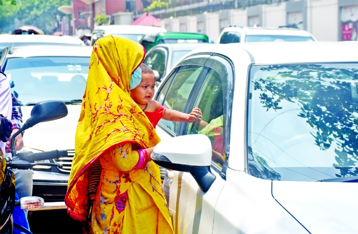 A woman with her baby on lap begs for alms near a private car as unemployment and loss of livelihood have forced many people to start begging in the capital. This photo was taken from in front of the Secretariat on Wednesday.
